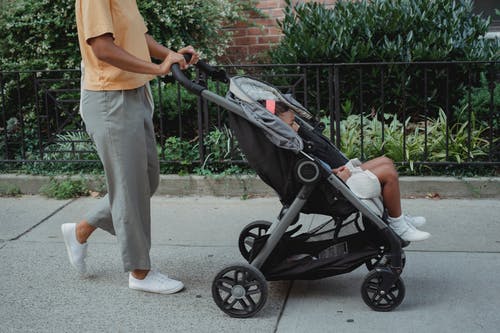作物女人带着孩子在婴儿推车走 · 免费素材图片