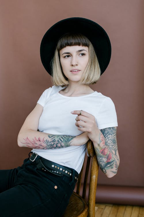 戴着黑帽子和白衬衫，坐在椅子上的女人 · 免费素材图片