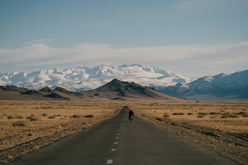 柏油马路和丘陵后面的雪山 · 免费素材图片