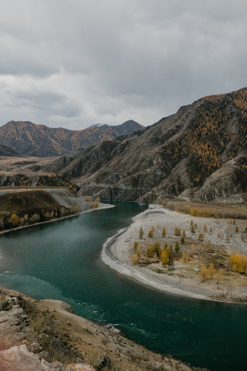 在崎rough的山区地形中的平静河 · 免费素材图片