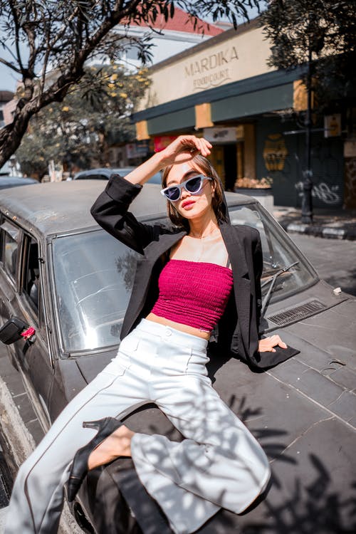 时尚的年轻女子坐在汽车引擎盖上 · 免费素材图片