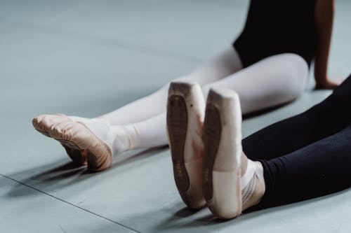 在演播室的芭蕾舞蹈期间播种舒展脚的妇女和女孩 · 免费素材图片