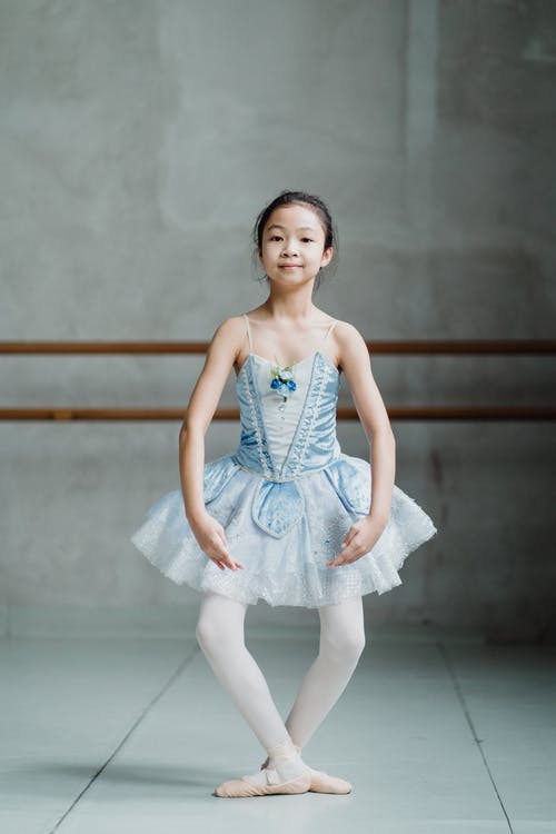 微笑的亚裔芭蕾舞女演员女孩在芭蕾舞学校表演plie · 免费素材图片