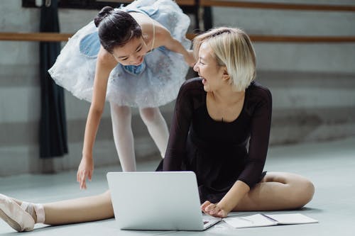 芭蕾舞短裙的快乐的种族女孩与教练冲浪的膝上型计算机 · 免费素材图片
