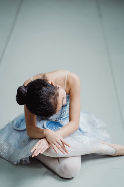 芭蕾舞短裙的女孩在与交叉的双腿和手臂的地板上 · 免费素材图片