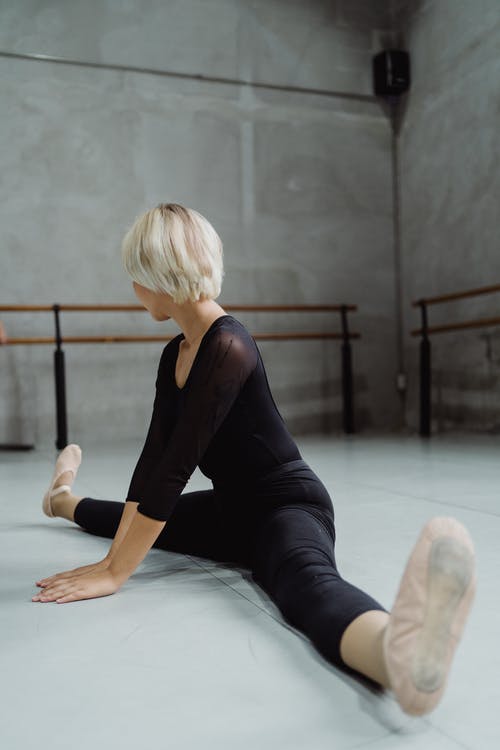灵活的芭蕾舞演员在地板上做拆分 · 免费素材图片