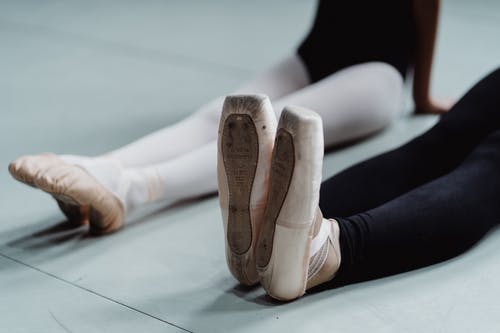 匿名女舞者指出在工作室里的地板上伸展双腿 · 免费素材图片