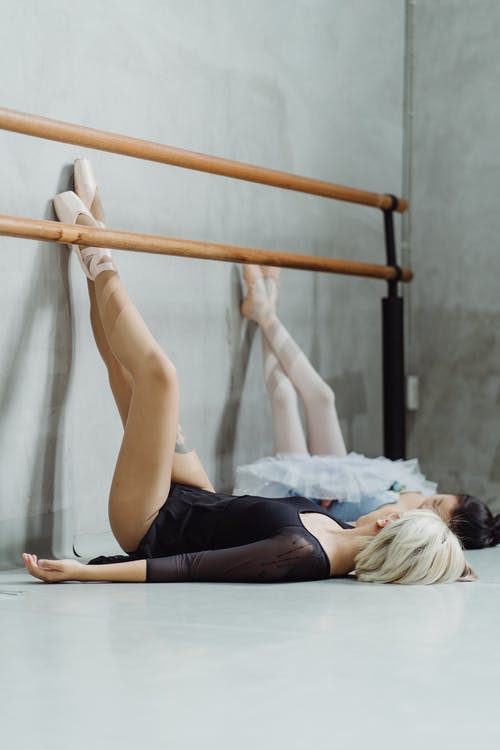 优雅的芭蕾舞演员在工作室的墙上休息的双腿 · 免费素材图片