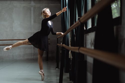芭蕾舞女演员站在工作室里的巴雷附近的一条腿脚趾 · 免费素材图片
