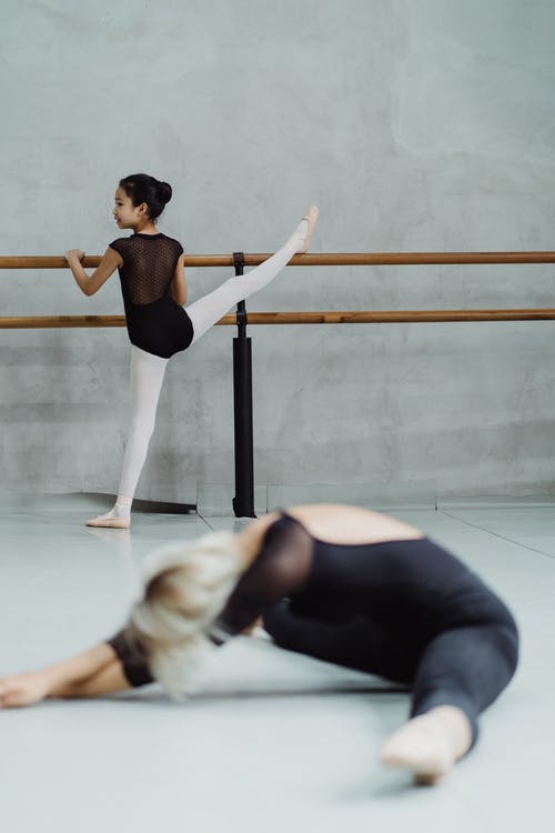舒展腿的芭蕾舞女演员女孩在演播室 · 免费素材图片