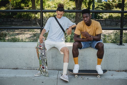 运动多样的男性朋友与滑板在公园里休息 · 免费素材图片