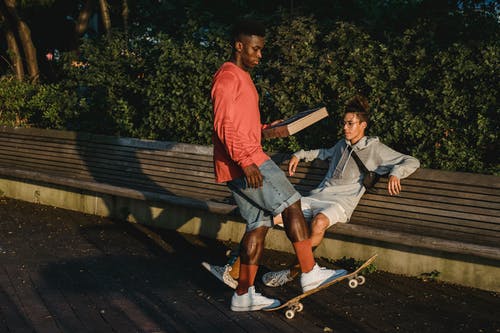 多种族的男性滑板与披萨盒和滑板在公园 · 免费素材图片