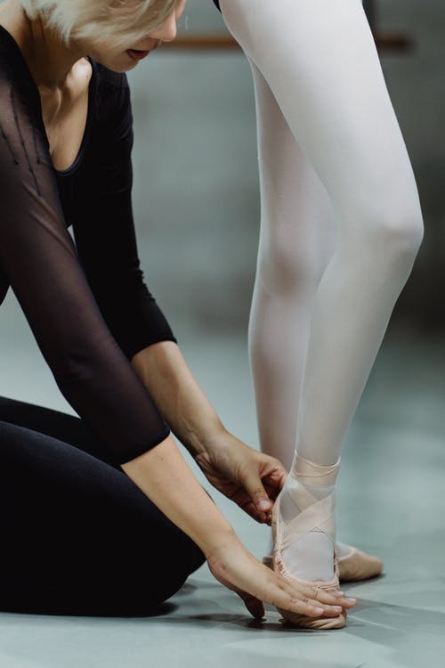 作物芭蕾舞指导员触摸学员的脚并讲解动作技巧 · 免费素材图片