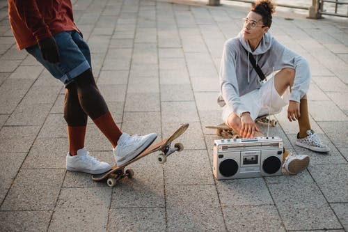 不同的男性溜冰者与滑板和音箱在路堤上休息 · 免费素材图片
