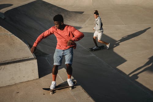 年轻人在阳光下在斜坡上整理滑板特技 · 免费素材图片