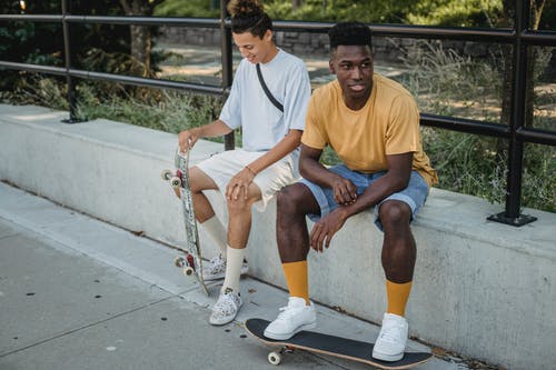 性格开朗的多样溜冰者一起在人行道上休息 · 免费素材图片