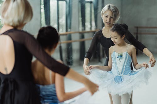 亚洲芭蕾舞教练和芭蕾舞短裙站在反对镜子的女孩 · 免费素材图片
