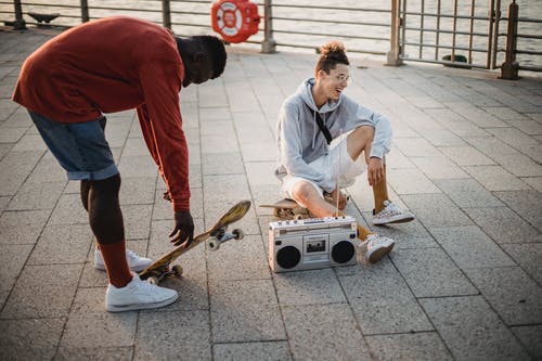 性格开朗的多种族男性溜冰者通过boombox听听音乐 · 免费素材图片