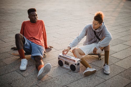 时尚年轻多样的男性朋友，滑板后在大街上放松和调整音箱 · 免费素材图片