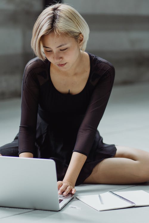 亚洲女人在地板上使用笔记本电脑 · 免费素材图片