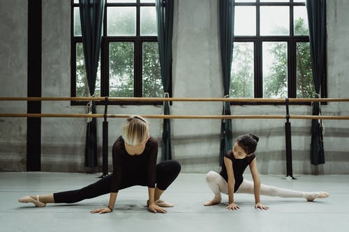 亚洲芭蕾舞女演员在宽敞的工作室在地板上伸展双腿 · 免费素材图片