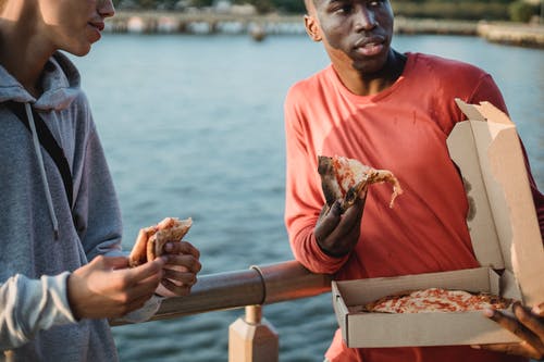 作物多样化的男人在路堤上吃美味的比萨 · 免费素材图片