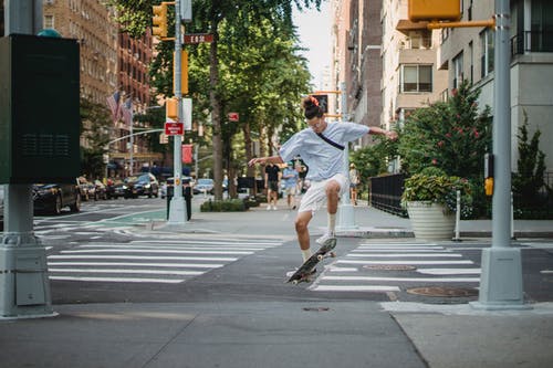 熟练的滑板手在城市街道上的滑板上表演技巧 · 免费素材图片