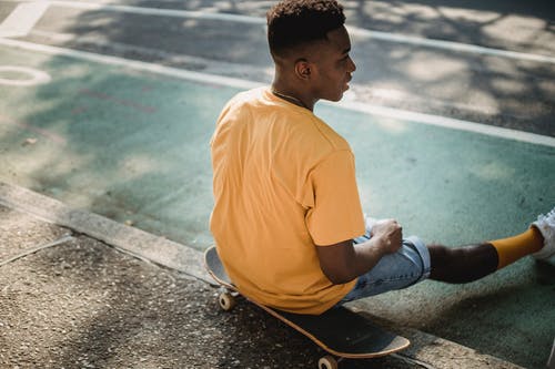 在阳光下锻炼后坐在滑板上的时髦黑人 · 免费素材图片
