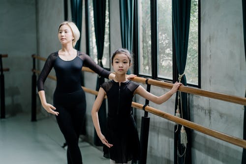 亚洲女孩在大厅里进行芭蕾锻炼期间的芭蕾舞老师 · 免费素材图片