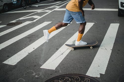 在人行横道上的黑人男子骑滑板 · 免费素材图片