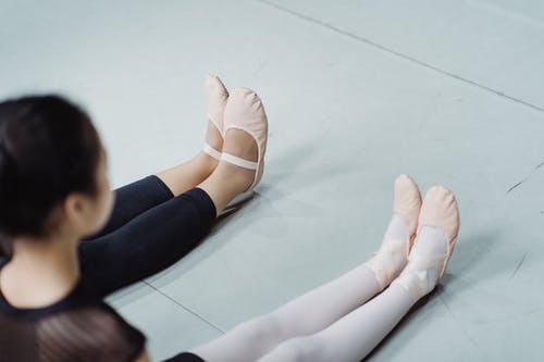 坐在工作室的地板上的芭蕾舞拖鞋的作物芭蕾舞女演员 · 免费素材图片