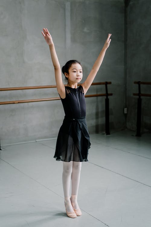 站立与胳膊的亚裔女孩芭蕾舞女演员在演播室上升了 · 免费素材图片
