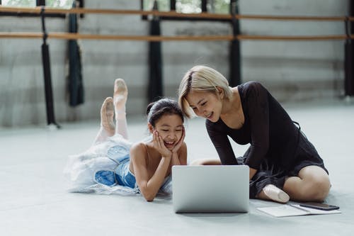 有女孩的快乐的种族妇女浏览膝上型计算机在芭蕾演播室 · 免费素材图片