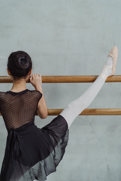 不可识别的女孩在芭蕾课上在巴里伸展腿 · 免费素材图片
