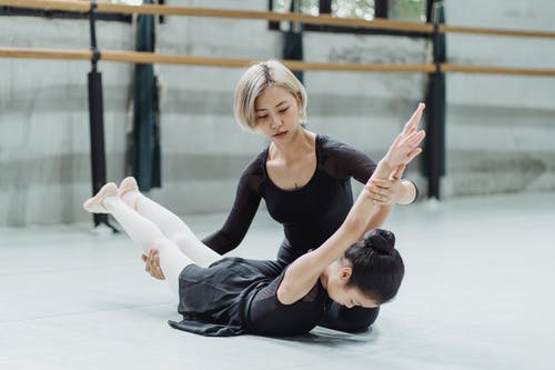 族裔女老师在芭蕾舞锻炼过程中支持学生 · 免费素材图片