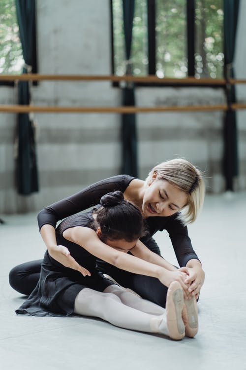 积极的亚洲芭蕾舞老师帮助女孩实习生伸展身体 · 免费素材图片