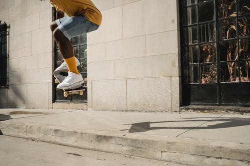 裁剪非洲裔美国运动的人，在阳光下跳上滑板 · 免费素材图片
