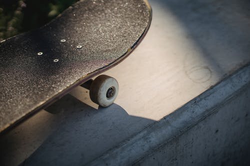 在阳光下的混凝土表面上破旧的黑色滑板鼻子 · 免费素材图片