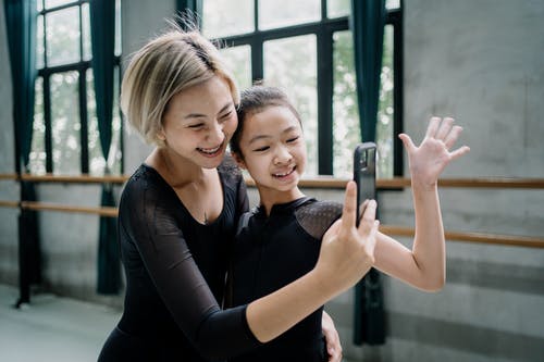 快乐的亚洲芭蕾舞演员在工作室的智能手机上采取自拍照 · 免费素材图片