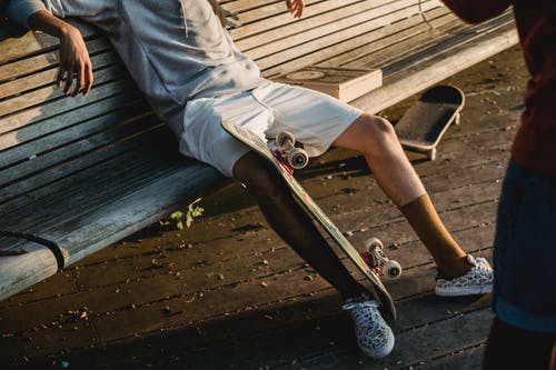作物不露面男溜冰者与滑板在长凳上休息 · 免费素材图片