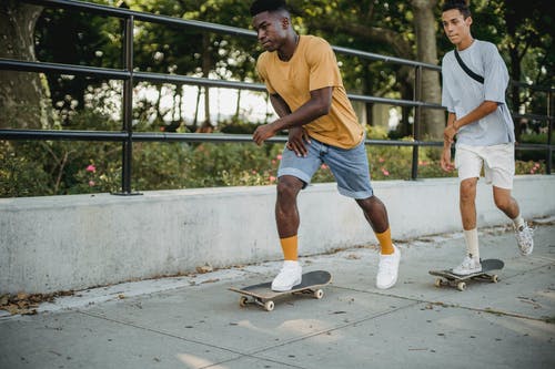 不同的男性朋友一起在城市骑滑板 · 免费素材图片