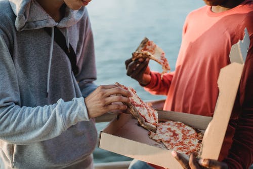 作物变得面目全非的人在江边吃披萨 · 免费素材图片