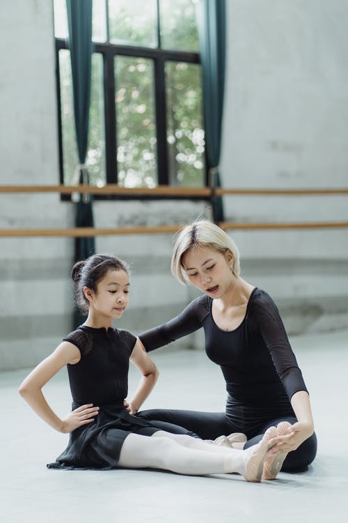 亚洲芭蕾舞女演员帮助女孩与芭蕾舞蹈在舞厅 · 免费素材图片