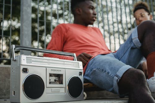 黑人和朋友一起坐，在复古盒式录音机上听音乐 · 免费素材图片
