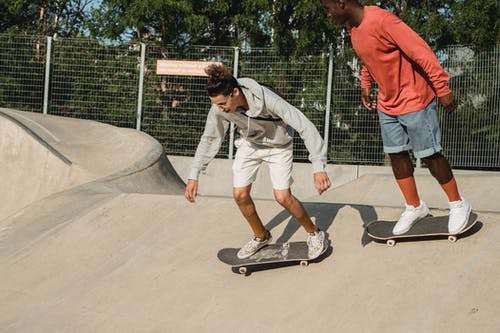 年轻人在坡道地面上休闲装滑板 · 免费素材图片