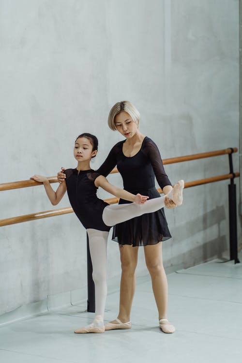 集中亚洲芭蕾舞演员帮助小女孩在巴利附近做舞蹈动作 · 免费素材图片