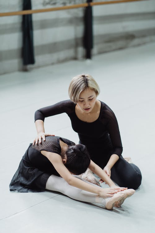 在芭蕾舞课上伸展无法认出的瞳孔的亚洲教练 · 免费素材图片