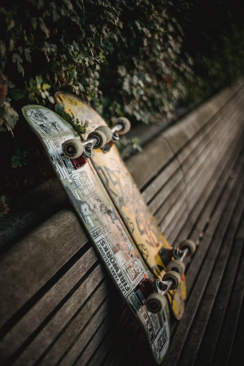 滑板放在绿色公园的木凳上 · 免费素材图片