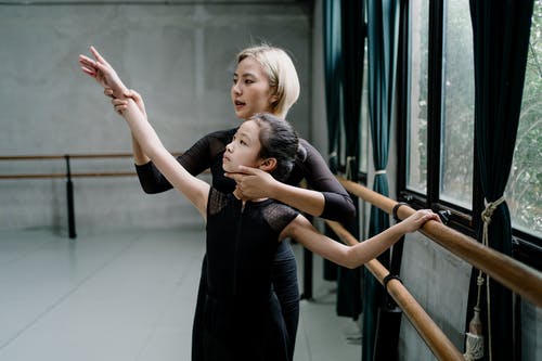 亚洲芭蕾舞老师在大厅训练期间与学生互动 · 免费素材图片