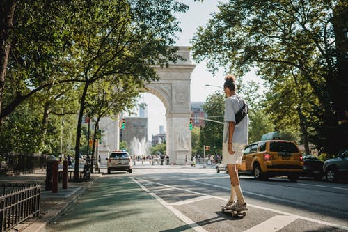 不可识别的运动型家伙骑滑板在城市的街道上，在白天 · 免费素材图片